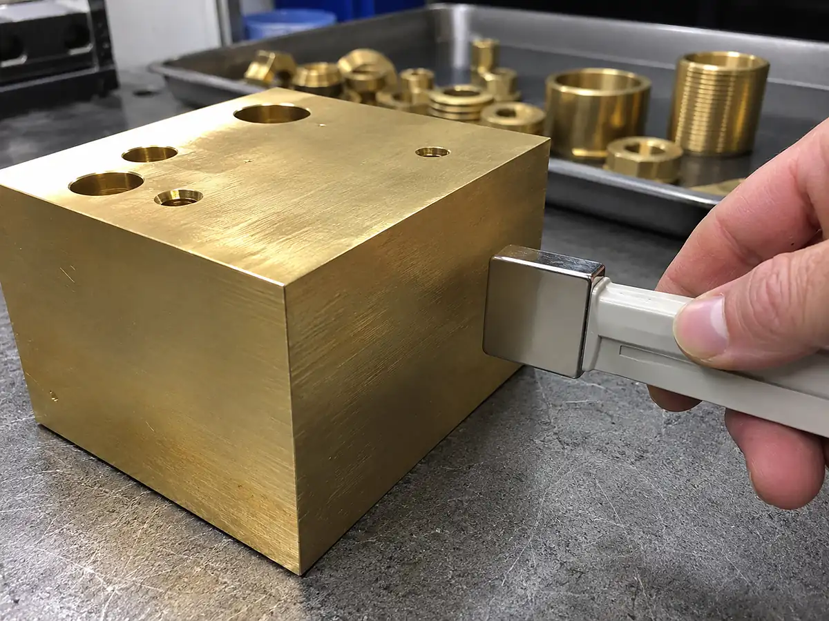 Handheld neodymium magnet testing a solid brass machined block